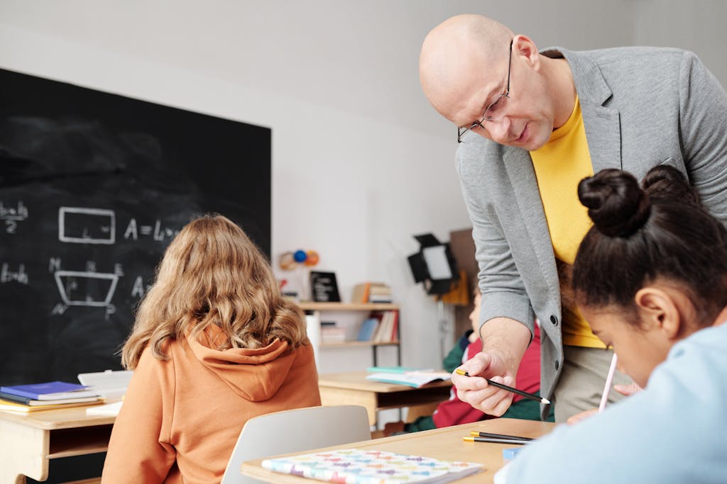 Teacher helping students in classroom, enhancing learning with personalized attention.