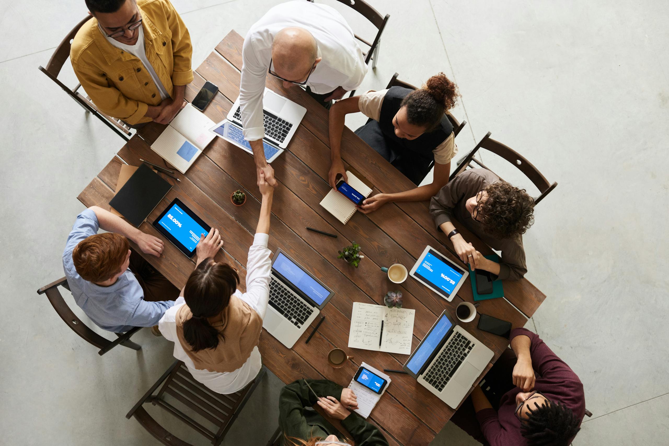 Photo by fauxels Top view of a diverse team collaborating in an office setting with laptops and tablets, promoting cooperation.