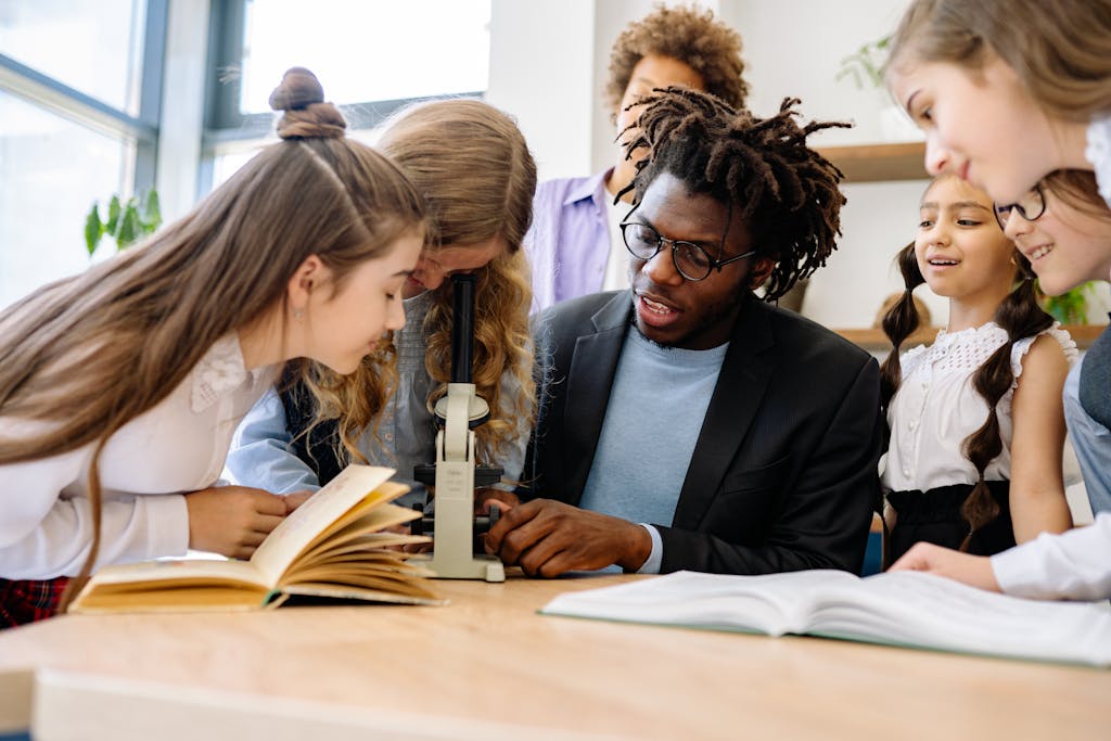 Students and teacher engage in science lesson using a microscope, fostering curiosity and learning.